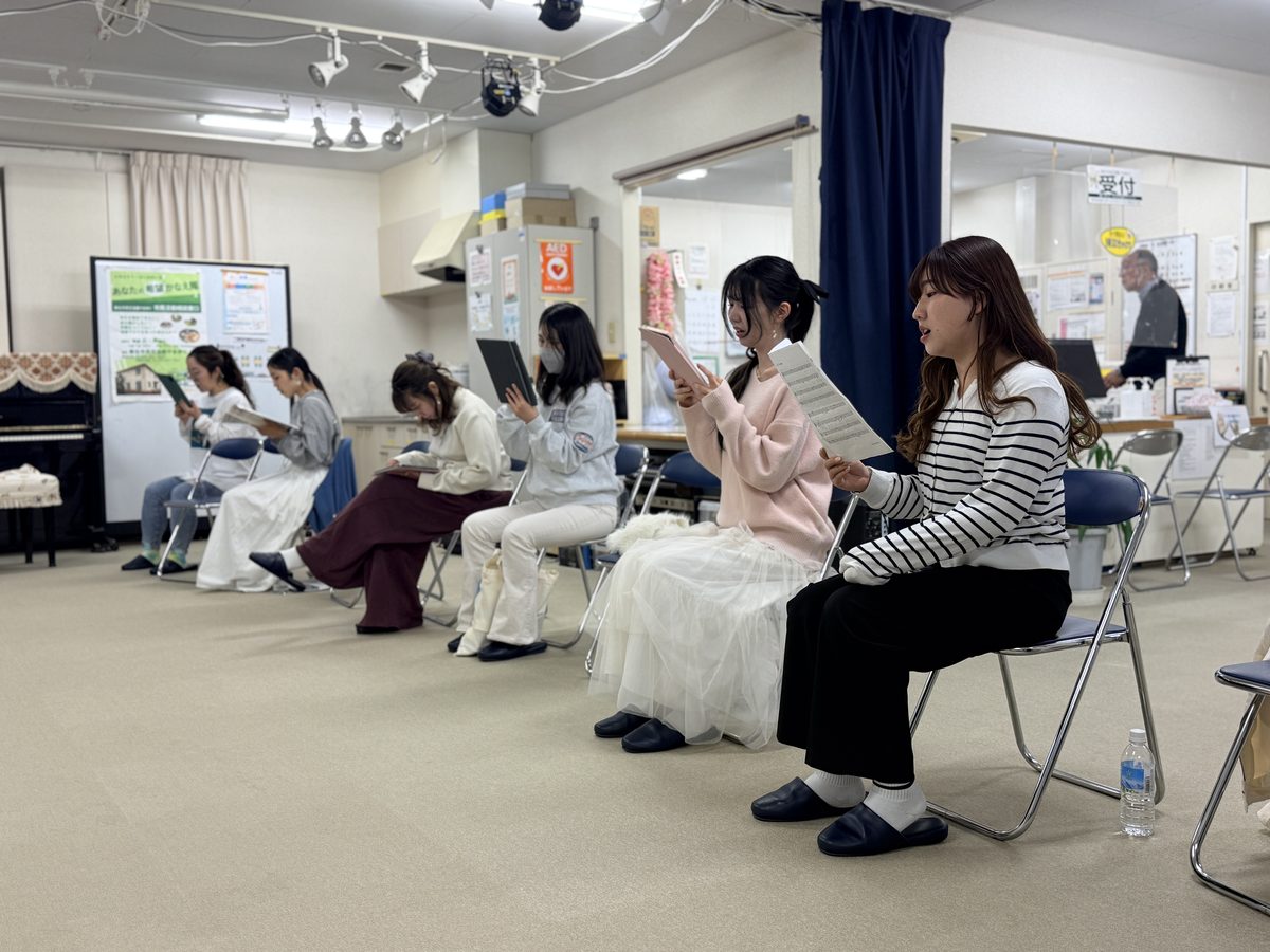 練習室で楽譜を手に歌う団員たち